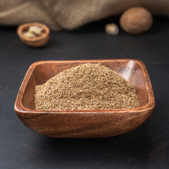 spices seasonings and grains on a square wooden bowl on a dark background and burlap
