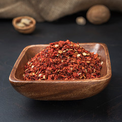 spices seasonings and grains on a square wooden bowl on a dark background and burlap