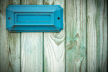 Blue rectangular address plate / mailbox on an old shabby turquoise fence