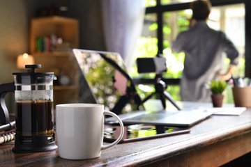 A coffee press and a cup on a work desk with a person working from home