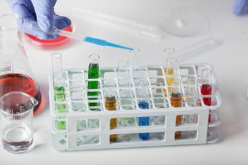 Lab. A lab technician in rubber gloves drops the reagent into the tested sample