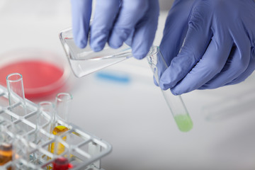 Lab. A technician in rubber gloves performs a reaction using a solvent