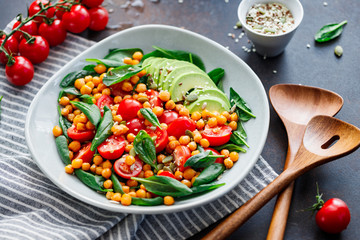 Fresh healthy salad with chickpea, avocado, cherry tomatoes and spinach.