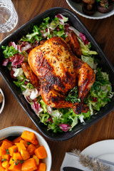 Top view of decorated festive table with whole roasted chicken, salad, pumpkin and mushrooms. The concept of family dinner or Thanksgiving celebrate.