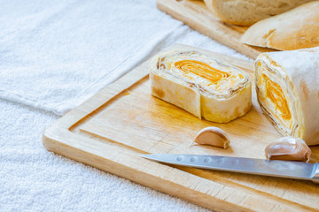 Sliced roll of Armenian pita bread with carrot filling on a wooden board.