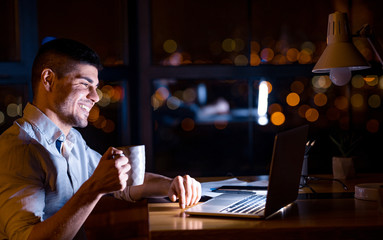 Happy Entrepreneur Sitting At Laptop Having Coffee At Workplace
