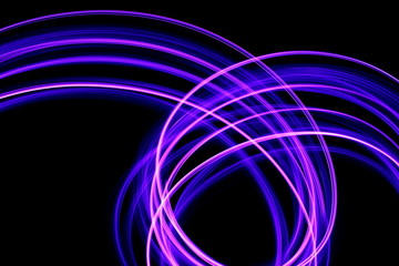 Long exposure photograph of neon purple streaks of light in an abstract swirl, parallel lines pattern against a black background. Light painting photography.