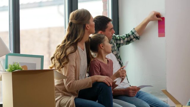mortgage, family and real estate concept - happy mother, father and little daughter with color palette and stuff in boxes moving to new home