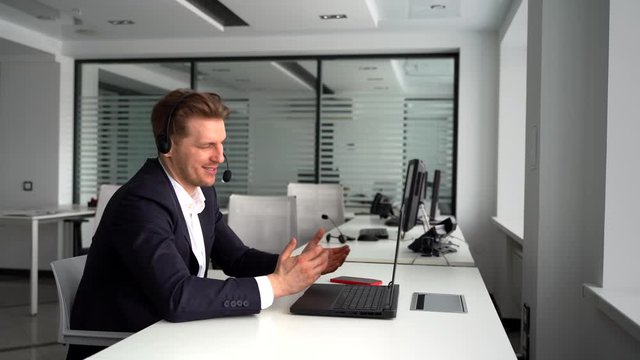 Happy businessman with laptop and headset talking during video conference