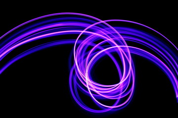 Long exposure photograph of neon purple streaks of light in an abstract swirl, parallel lines pattern against a black background. Light painting photography.
