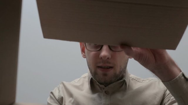 Man opens the box, looks around and steals on the sly the contents of box