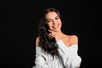 Young woman with beautiful healthy hair on dark background