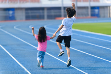 Obraz premium Young boy and girl play on a bluetrack after running