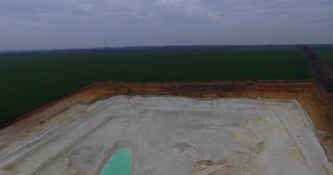 Aerial view of open pit kaolin clay mine (kaolinite quarry) with turquoise pool of water
