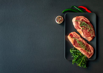 Raw beef meat on the table with ingredients for cooking.  Space for text. Beef Rib eye steak, top view. Barbecue concept. Ingredients for roasting meat.