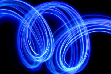 Long exposure photograph of neon purple streaks of light in an abstract swirl, parallel lines pattern against a black background. Light painting photography.
