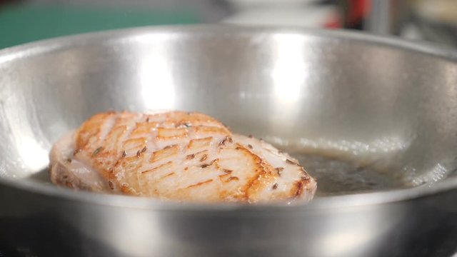 Duck meat being fried in hot pan with olive oil. Slow motion footage. Cooking classic Confit Duck in French restaurant, close-up. Shot in hd.