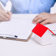 Business concept - Young Asian man in blue shirt calculates, signs agreement contract to buy a house loan payment, paying insurance, tax, close up.