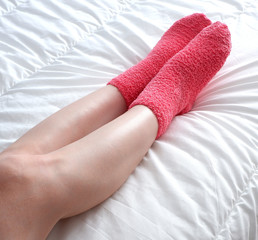 Beautiful smooth legs protrude from under the blanket, in soft pink socks.