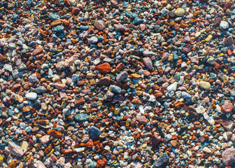 Wet colored pebbles on a beach in the surf