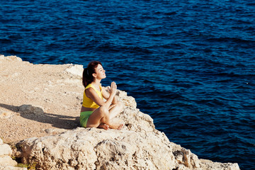 girl doing yoga on the beach by the sea