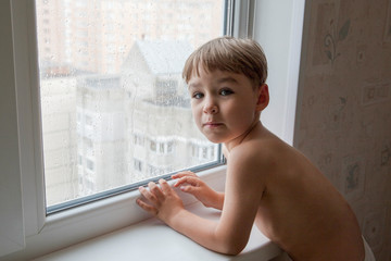 little boy watching the rain through the window. close-up	