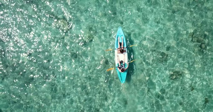 Top Down Aerial View Shoot As Couple Paddle Their Blue White Kayak In Clear Sea Water With Corals, Summer Time, Tropical Area, Water Touristic Activity In Thailand