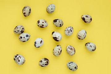 Chaotic pattern of easter quail eggs on a yellow background. Happy easter banner