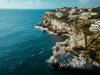 Drone panoramic image moored yachts on bright blue bay Cala Blanca Andratx, Palma de Mallorca, rocky coast breathtaking view, Balearic Islands Spain.