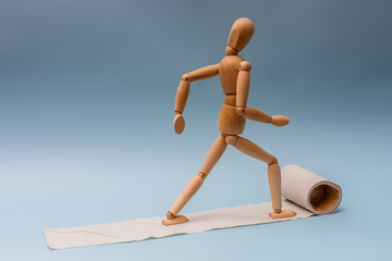 A wooden man is walking on toilet paper