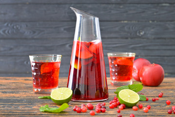 Jug and glasses of tasty cold tea on wooden table