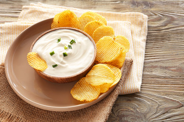 Tasty sour cream and potato chips on table