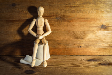 Wooden figure sit on a roll of toilet paper. Concept of the problem with digestion.