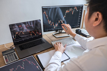 Stock exchange market concept, Business investor trading or stock brokers having a planning and analyzing with display screen and pointing on the data presented and deal on a stock exchange