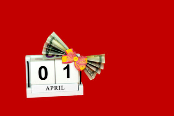 dollar tied with a festive bow. American currency, paper currency notes. perpetual calendar with wooden cubes. the concept of celebrating the birthday of the dollar on April 01. red holiday background