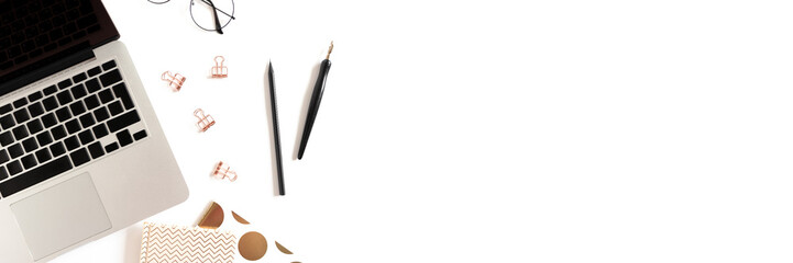 Office desk with laptop, golden notepads, glasses and stationery on a white background.