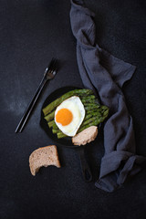 Organic healthy Asparagus and fried egg served in a frying pan. Healthy vegetarian breakfast. Black background. Copy space. Flat lay. Vertical