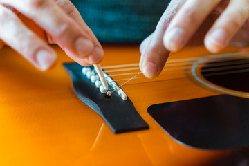 Detail of unrecognizable professional music teacher explaining step by step instructions to change acoustic guitar strings. Music course online concept. Indoor leisure lifestyle for young people.