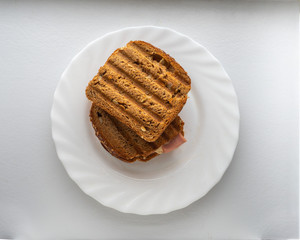 Grilled closed sandwiches with sausage and cheese for a quick lunch, served on a white plate