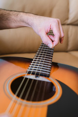 Fototapeta premium vertical detail of unrecognizable professional music teacher explaining step by step instructions to change acoustic guitar strings. Music course online concept. Indoor leisure lifestyle