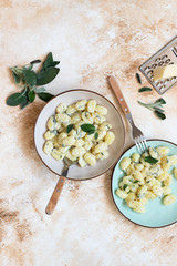 Italian homemade gnocchi with butter, cheese and sage served in two plates on a light marble table. Italian food. Copy space. Vertical. Flat lay