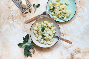 Italian homemade gnocchi with butter, cheese and sage served in two plates on a light marble table. Italian food. Copy space. Flat lay