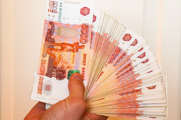 Paper bills denominated in five thousand rubles. Hands count money