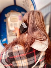 Fototapeta premium a girl in a protective mask near public phone during quarantine