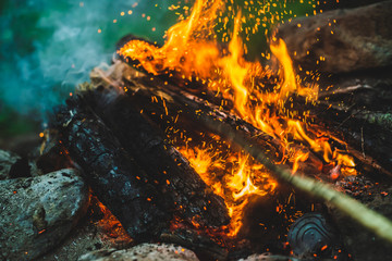 Vivid smoldered firewoods burned in fire close-up. Atmospheric background with orange flame of...