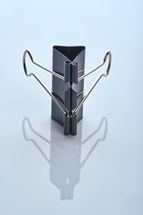 metal stationery binder stands on a white reflective surface