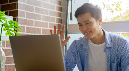 close young asian man video conference with others people via program on laptop in coronavirus...