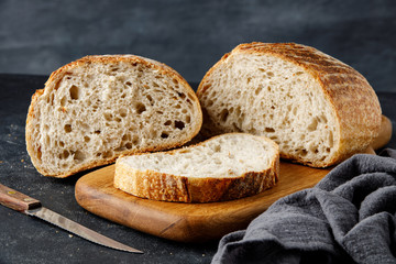 Sliced bread on a wooden cutting board, two halves of wheat bread. Traditional wheat freshly rustic baked bread.