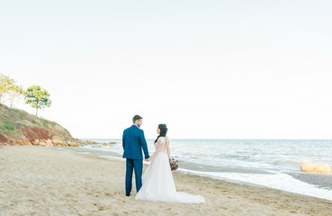 Bride and groom at wedding Day on the beach near the sea. Smiling bride and groom. Young couple in love hugging near sea shore