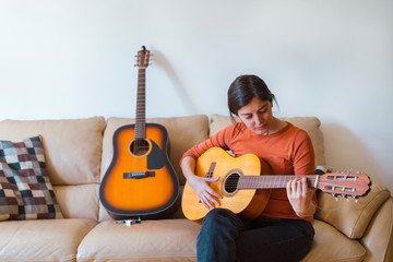 Beautiful caucasian female learning how to play an instrument. Leisure and music at home concept....